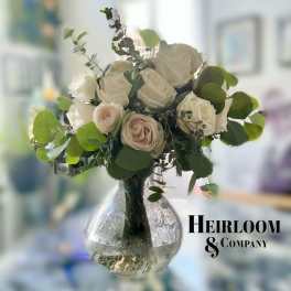 White and blush roses in a clear glass vase with greenery