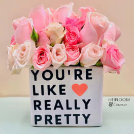 Pink and white roses in a square vase with a printed message