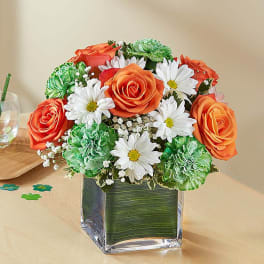 Orange roses and white daisies in a square glass vase