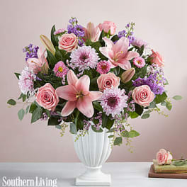 Pink and purple floral arrangement in a white pedestal vase