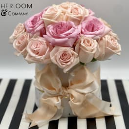Pink and blush roses arranged in a white hat box with a satin bow