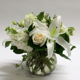 White lilies and a cream rose in a glass vase