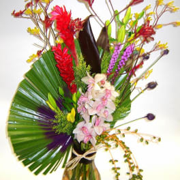 Tropical bouquet with orchids and red flowers in a glass vase