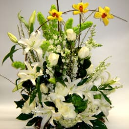 White lilies and roses with yellow orchids in a tall arrangement