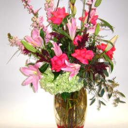 Pink lilies and red blooms in a tall glass vase