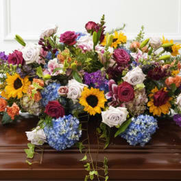 Colorful floral casket spray with roses, sunflowers, and hydrangeas