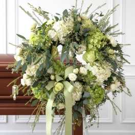 Large green and white funeral wreath on a stand with ribbon