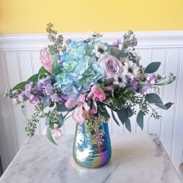 Pastel bouquet with hydrangeas, roses, and daisies in an iridescent vase