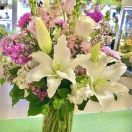 Tall bouquet of white lilies and pink flowers in a glass vase