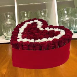 Heart-shaped arrangement of red and white roses in a red box