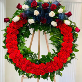 Red and white rose wreath on an easel with a navy bow