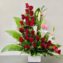 Tall arrangement of red roses and white lilies in a white vase