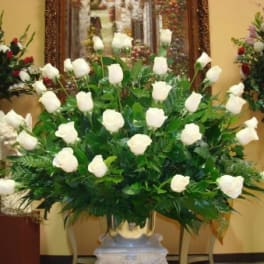 Large white rose arrangement in a gold vase with greenery