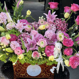 Large pink and yellow floral arrangement in a decorative wooden container