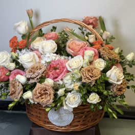 Basket of pink, white, and peach roses with greenery