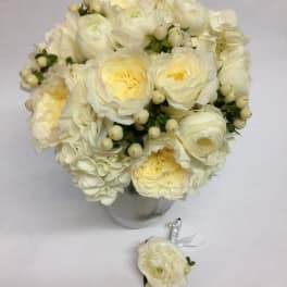 White rose bouquet in a glass vase with a matching boutonniere below