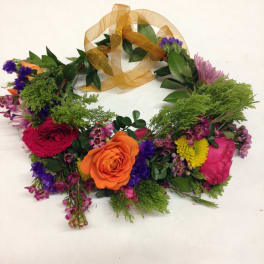 Floral wreath with roses and mixed blooms tied with a gold ribbon