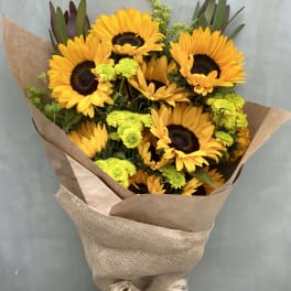 Bouquet of sunflowers and green button mums wrapped in brown paper