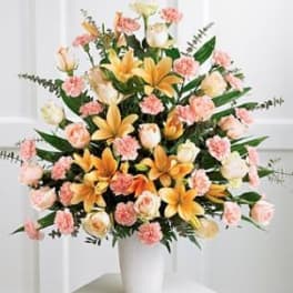 Pink and yellow floral arrangement in a white vase