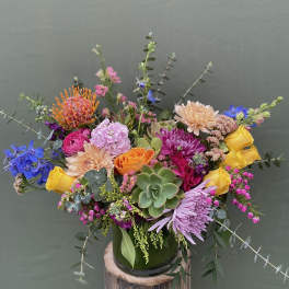 Colorful mixed bouquet in a green glass vase with a succulent centerpiece