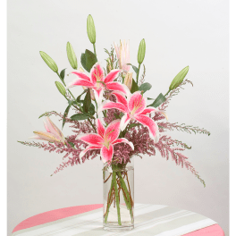 Pink lilies in a clear glass vase with unopened buds