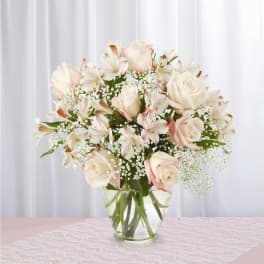 Blush roses and white alstroemeria in a clear glass vase