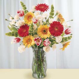 Mixed bouquet of red and yellow flowers in a clear glass vase