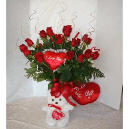 Red roses arranged with heart decorations and a teddy bear