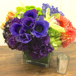 Colorful bouquet of mixed flowers in a square glass vase