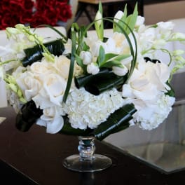 White roses and orchids arranged in a clear glass vase