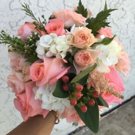 Handheld bouquet of pink and peach roses with white hydrangeas
