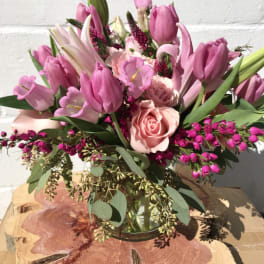 Pink tulips and roses arranged in a clear glass vase