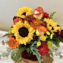 Bouquet of sunflowers, roses, and mums in a glass vase