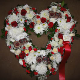 Heart-shaped floral wreath with red and white flowers and a red ribbon