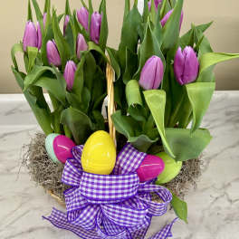 Purple tulips in a basket with colorful Easter eggs and a gingham ribbon