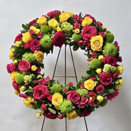 Circular floral wreath of pink and yellow roses on a stand