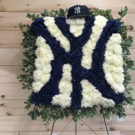 Large floral tribute in navy and white with a baseball cap on top