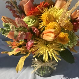 Bouquet of yellow, orange, and pink flowers in a glass vase