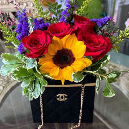 Red roses and a sunflower in a black gift bag arrangement
