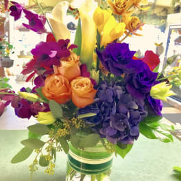 Colorful bouquet with roses, calla lilies, orchids, and hydrangea in a glass vase