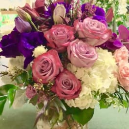 Bouquet of pink and purple roses with white hydrangea in a glass vase
