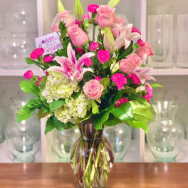 Pink roses and lilies arranged in a clear glass vase