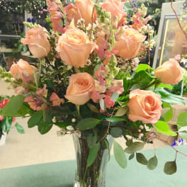 Peach roses arranged in a clear glass vase with pink snapdragons