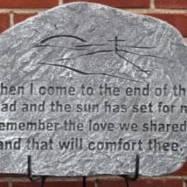 A painted memorial stone with a quote on a brick wall