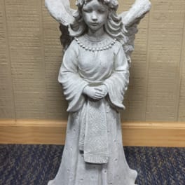 White angel statue with folded hands standing indoors
