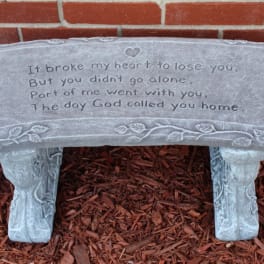 Gray memorial bench with an engraved sympathy message