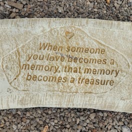 Memorial stone with an engraved quote on a gravel surface