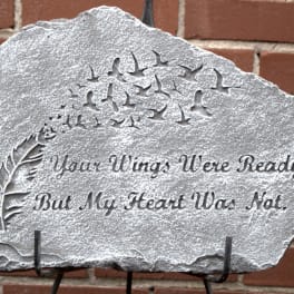 Engraved memorial stone with birds and a feather design