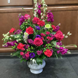 Large mixed floral arrangement in a white urn vase