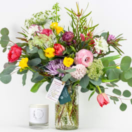 Mixed bouquet in a glass vase with a candle beside it